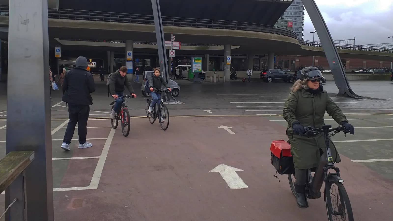 Een forens op een elektrische fiets met fietstassen, op het fietspad achter Amsterdam Centraal
